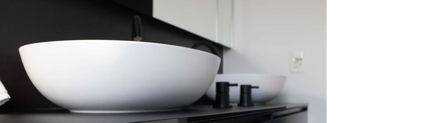 Lavabo bianco moderno su piano scuro in bagno contemporaneo, rubinetti neri e sfondo sfocato