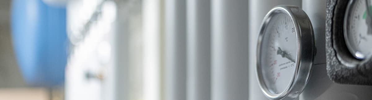 Immagine di colonne verticali sfocate in tonalità chiare e manometri in primo piano, atmosfera luminosa e minimale.